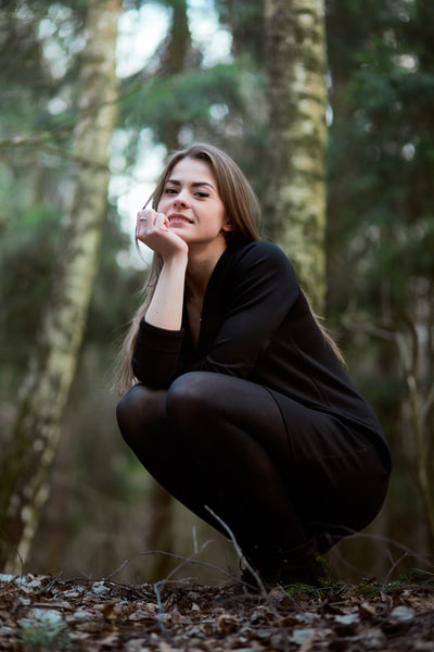 女人黑色长袖衬衫和黑裤子坐在树枝上
